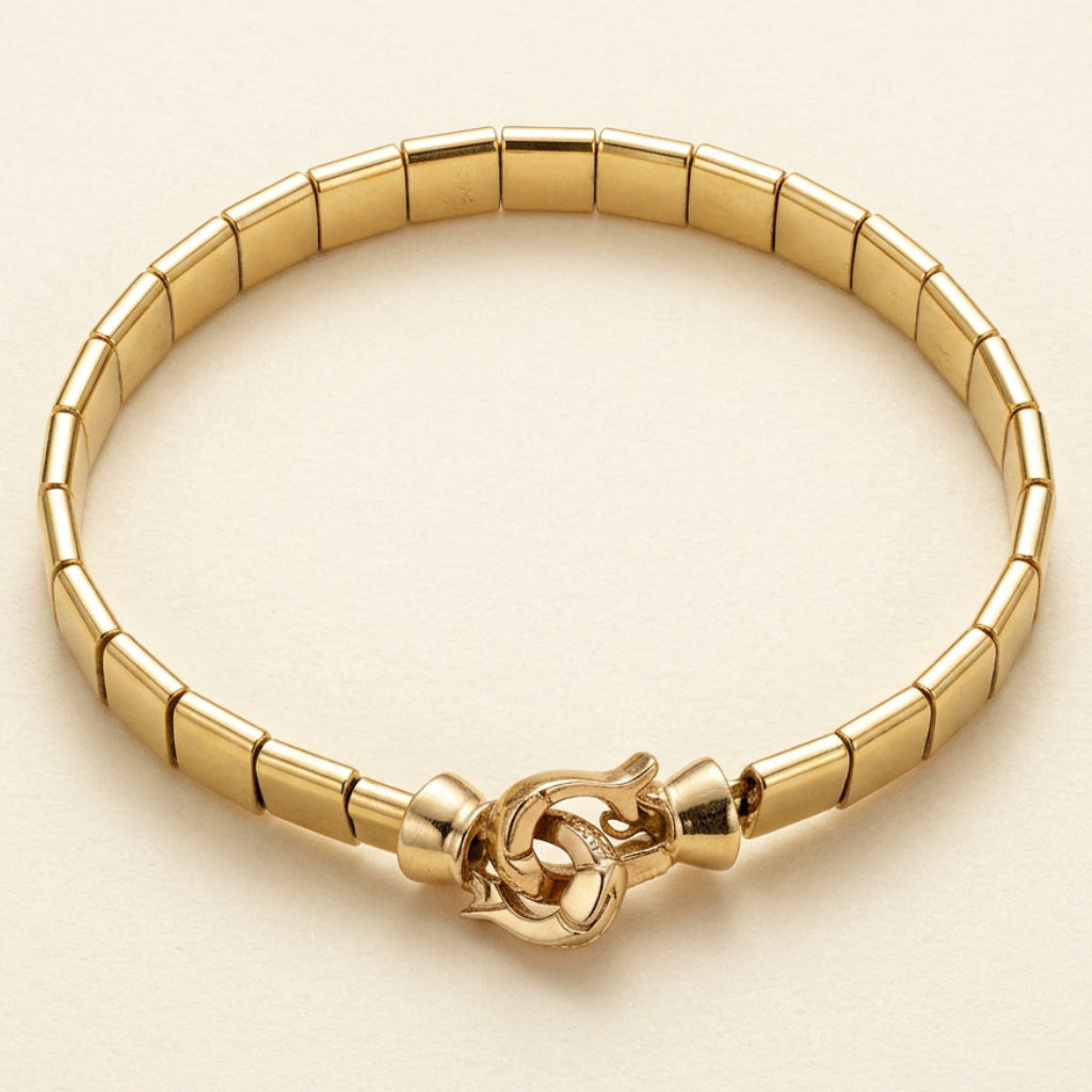 Aurum Line Slim bracelet with polished gold-tone rectangular beads and a lobster clasp on cream fabric.

