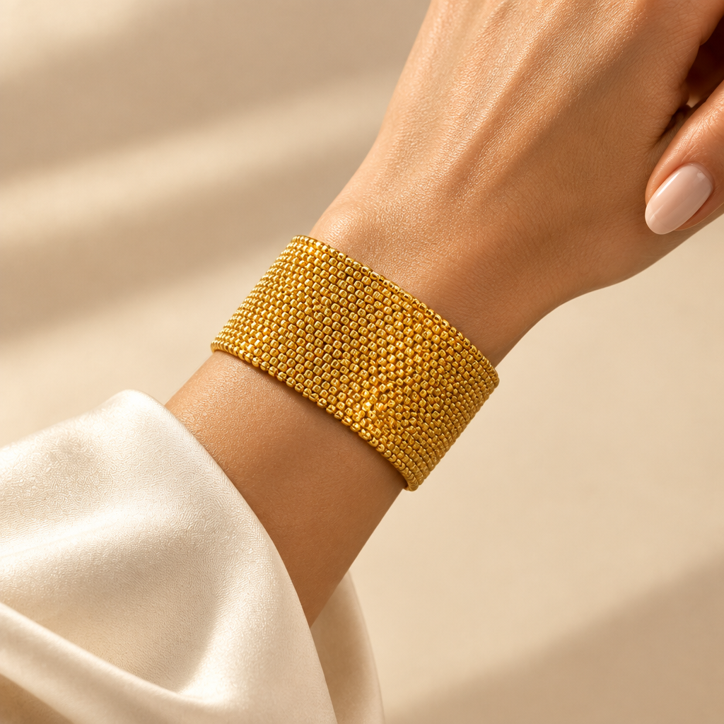 Éclat Doré wide gold Miyuki cuff worn on a woman’s wrist