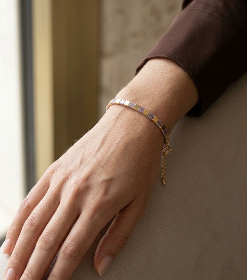 Mauve and gold slim geometric bracelet worn on a woman's wrist