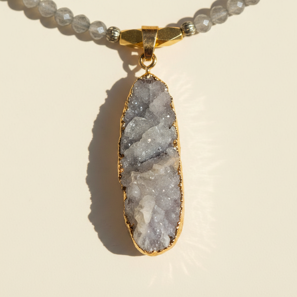 Macro detail of the organic gray druzy crystal pendant with a gold-plated edge.