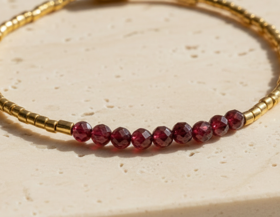 Macro detail of faceted garnet gemstones and polished gold beads.