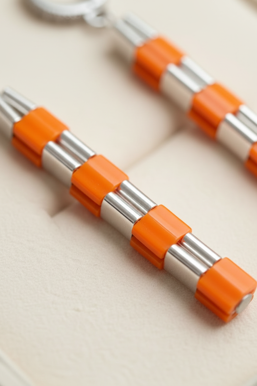 Macro detail of orange, white and metallic silver Japanese Miyuki Tila beadwork.